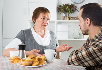 Elderly mother talking seriously and instructs her son at home