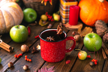 red mug with mulled wine. Cinnamon sticks stick out of the cup and a star of star anise floats....