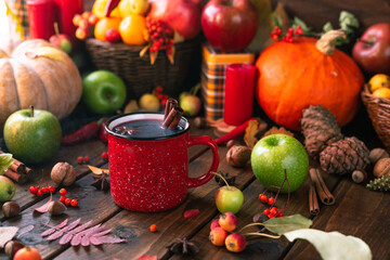 red mug with mulled wine. smoke comes from the mug. Cinnamon sticks stick out of the cup and a star...