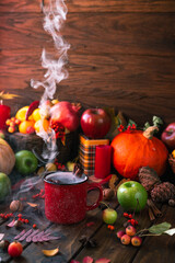 Obraz na płótnie Canvas red mug with mulled wine. smoke comes from the mug. Cinnamon sticks stick out of the cup and a star of star anise floats. Fruits and spices are all around on a wooden table