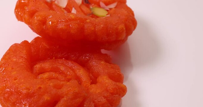 Deep fried all purpose flour batter dipped in sugar syrup sweet dessert red orange Jalebi jilapi Imarti on white background move slide rotate