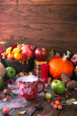 red mug with mulled wine. smoke comes from the mug. Cinnamon sticks stick out of the cup and a star of star anise floats. Fruits and spices are all around on a wooden table