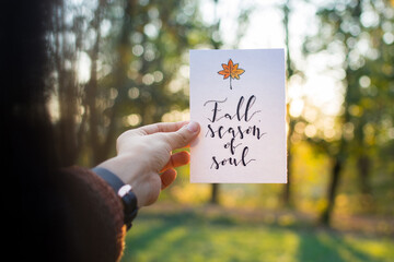 Girl holding an autumn card against the setting sun