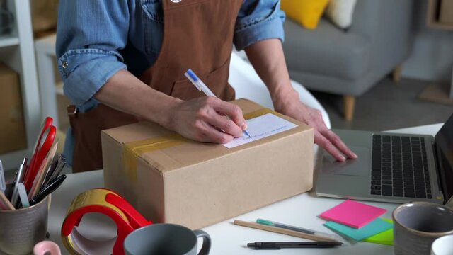 Mature Asian woman entrepreneur, Business owner writing client's address before shipping product. Online selling business