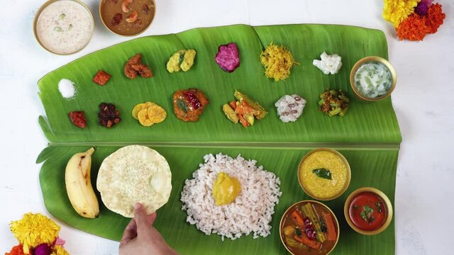 Woman hand serving curry for traditional Onam sadhya 4K footage video rice, Sambar, Rasam,  Avial,  Pappadom Payasam on banana leaf Onam Vishu Diwali festival vegetarian food Kerala South India 