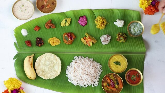 Woman hand serving  parippu dal curry ghee traditional Onam sadhya 4K footage video rice Sambar, Avial,  Pappadom Payasam on banana leaf Onam Vishu Diwali festival vegetarian food Kerala South India.