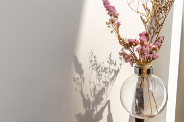 Beautiful dried flowers in a vintage glass vase for decoration at white brick background with empty wall with minimal Style. Copy space.