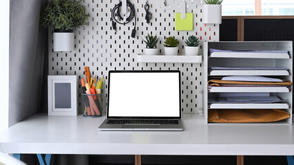 Computer laptop and office supplies on white table.