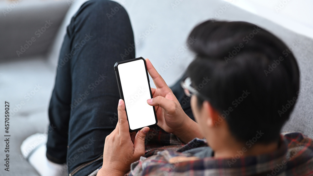 Poster man lying on comfortable sofa and using smart phone.