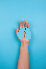 Women's hands hold a paper lungs symbol on blue background. Concept of World Tuberculosis Day or...