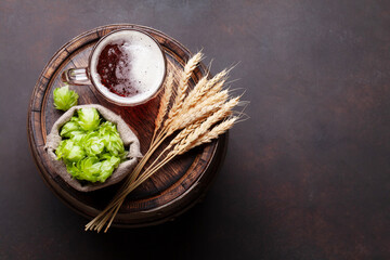 Lager beer mug, hops and wheat on old wooden barrel