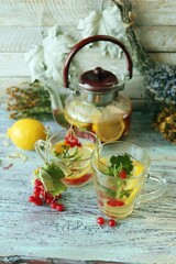 Tea with healthy herbs, flowers, berries and lemon in a glass cup on a wooden background