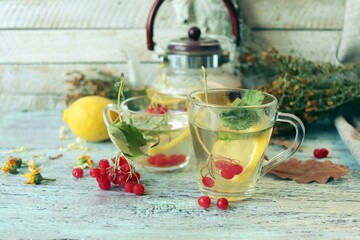 Tea with healthy herbs, flowers, berries and lemon in a glass cup on a wooden background