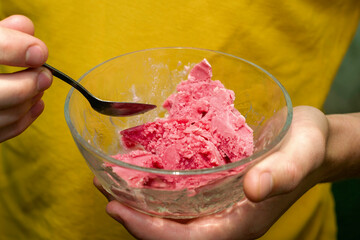 a man eats cherry ice cream with a spoon from an ice cream maker