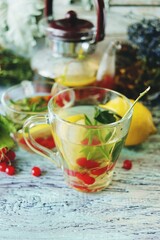 Tea with healthy herbs, flowers, berries and lemon in a glass cup on a wooden background