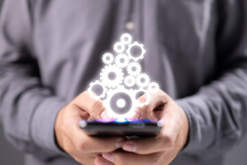 Businessman holding gears and smartphone in palms