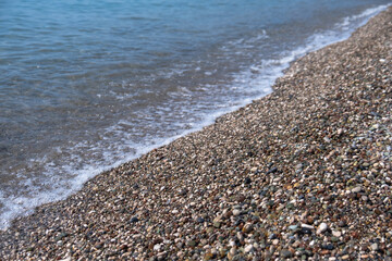 pebbles on the beach by the sea. transparent waves with foam,