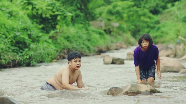 Children playing with friends in the river in countryside, Boys and girls smiling and happiness playing water at the countryside in Thailand.