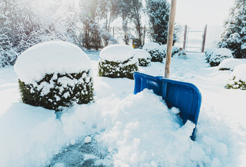 Snowy winter - blue shovel removing snow from the paver path (sidewalk)