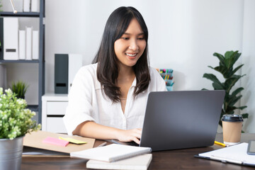 Business woman using laptop and sitting by the table in home office.