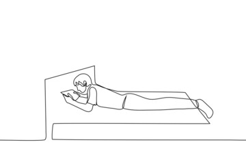 man lies on the bed with his stomach down and holds tablet with both hands, legs hanging from the edge of the bed - one line drawing. hobby for social networks, new gadget, watching movie or video