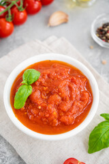 Traditional Italian marinara sauce in a bowl on a concrete background with spices and ingredients. Top view. Copy space.