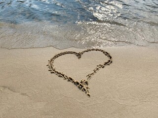 Heart on the sand. Heart on sandy beach by river shore. 