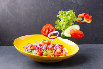 lettuce, tomatoes, onions, peppers on a dark background flying food