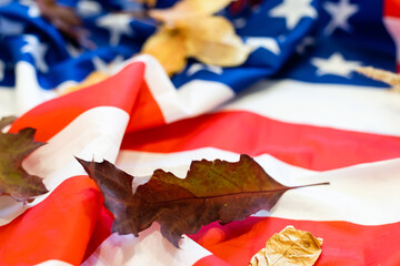USA flag buried in yellow dry leaves. Autumn texture.