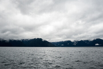Panoramic view of snow-capped mountains on a cloudy day and a lake on the bottom