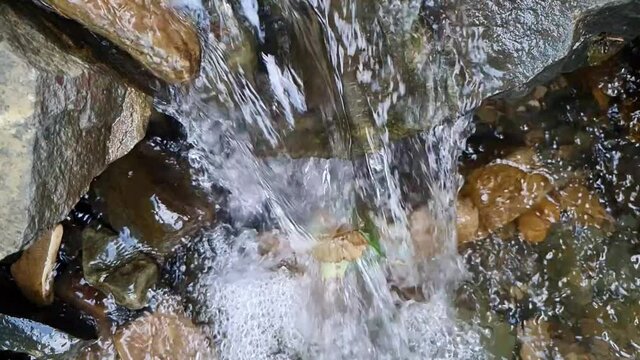 Slow motion top view of water stream flowing over rocks
