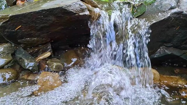 Slow motion of water stream flowing in the mountains over rocks