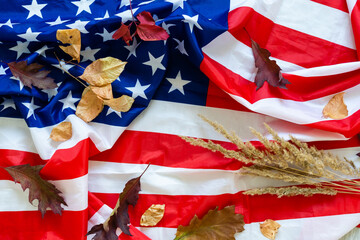 USA flag buried in yellow dry leaves. Autumn texture.