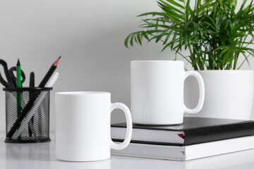 Two mugs mockup with accessories on white table. front view