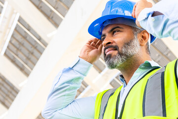 Hispanic engineer putting on safety helmet against solar power station