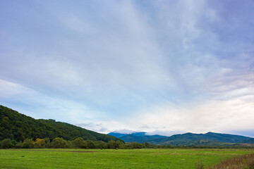 rural field in mountains at dawn. cloudy early autumn weather