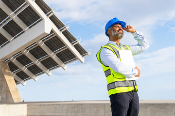 Hispanic engineer in helmet with clipboard working on solar power station