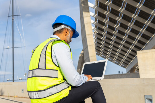Unrecognizable inspector working on laptop under modern solar power station