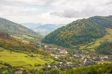 Fototapeta na wymiar rural landscape in mountains. cloudy autumn weather. village in the distant valley