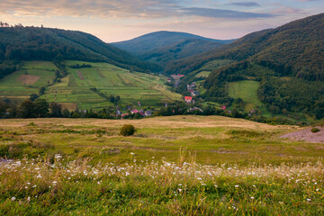 Fototapeta na wymiar mountainous countryside landscape at dawn. pastures and rural fields near the forest on the hills. beautiful early autumn nature scenery with clouds on the sky in morning light