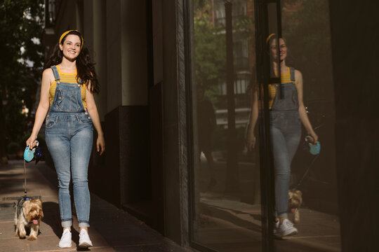 Smiling woman walking with purebred dog on leash
