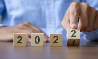 Man hand flipping of wooden cubes block to change 2021 to 2022 year. Merry Christmas and happy new year concept.