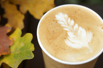 Cappuccino in a paper cup on a wooden table