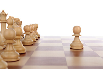 Pawn in front of other chess pieces on wooden board against white background