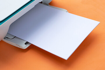 Printer and paper on orange background.