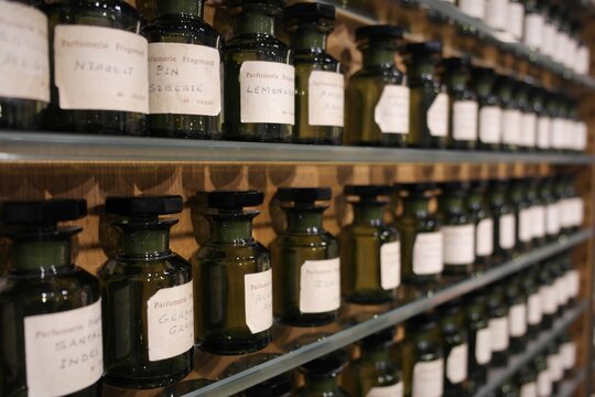 Opaque glass ingredient bottles (vial, flacon,containers) on shelves with essence extract substances, mix making french aroma perfumery.  Fragonard Museum, Paris inspiration history of  manufacturing