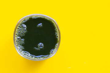 Glass of gotu kola leaves juice for health on yellow background. Copy space