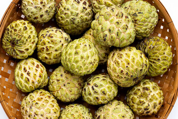 Custard apple in bamboo basket on white background.