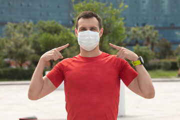 Fitness, sport and healthy lifestyle concept - young sporty man wearing face protective mask for protection from virus disease on city street. Coronavirus pandemic Covid-19.