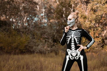 Girl dressed as a skeleton in the autumn forest. She stood awfully, staring at the camera. Halloween